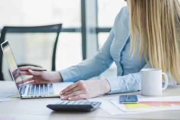 Zdjęcie przedstawia kobietę szykującą dokumenty do kontroli podatkowej.