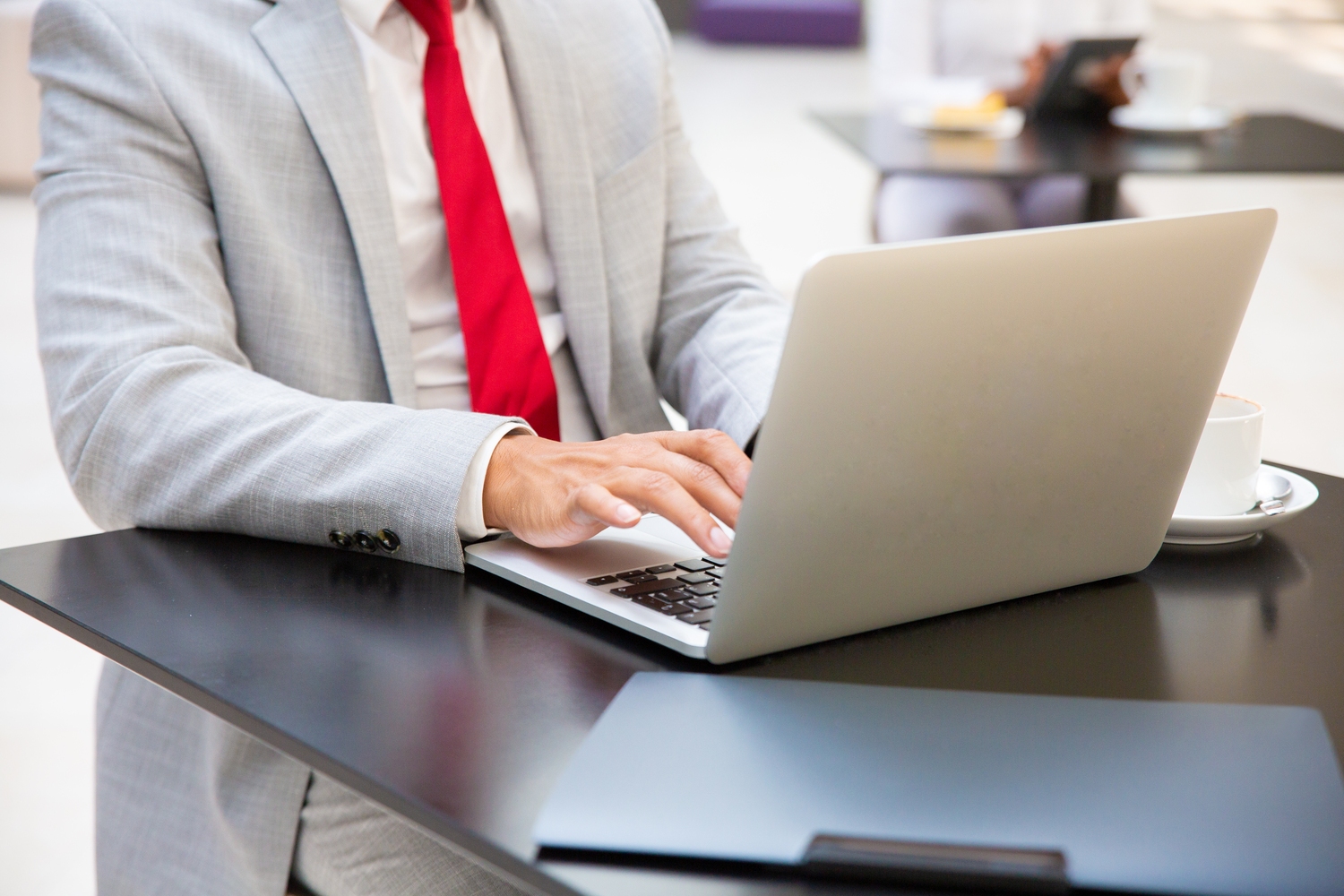 Zdjęcie przedstawia biznesmana przy laptopie załatwiającego ważne sprawy na nim.